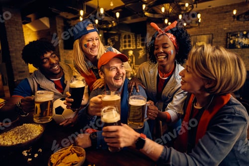 Preview: Diverse soccer fans celebrating their favorite team's victory with beer in a pub.