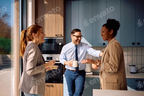Preview: Happy business colleague laughing while talking on coffee break in office kitchen.