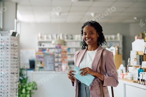 Preview: Portrait of happy black woman in a pharmacy looking at camera.