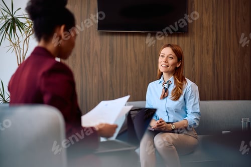 Preview: Happy businesswoman communicating with human resource manager during job interview at corporate offi
