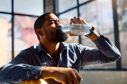 Preview: Thirsty construction worker drinking water from a bottle at work.