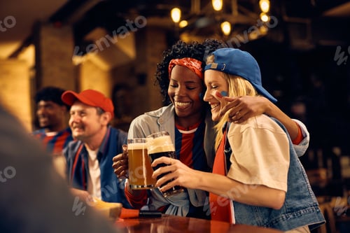 Preview: Happy female friends toasting with beer during sports championship.