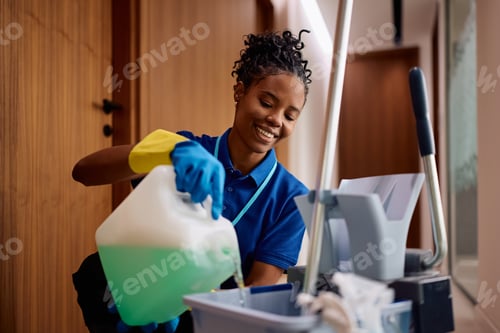 Preview: Happy black facilities maintenance worker pouring liquid cleaner into bucket.