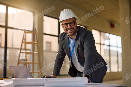 Preview: Happy architect working on housing development project and looking at camera.