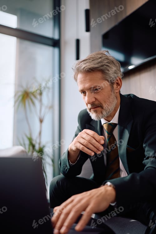 Preview: Mature CEO reading an e-mail on laptop while working in the office.