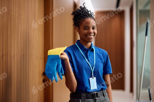 Preview: Happy black female cleaning professional at work looking at camera.