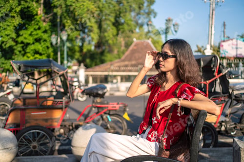 Preview: Young Indonesian Woman in Batik Fashion Relaxing Near Traditional Transport