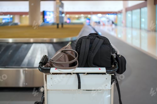 Preview: Luggage trolley with bags at airport baggage claim conveyor belt