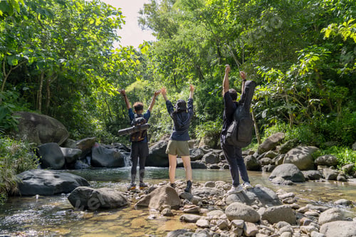 Preview: Hikers Celebrating in River Valley Surrounded by Tropical Forest