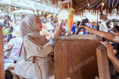 Preview: Indonesian Muslim woman paying with smartphone in cafe