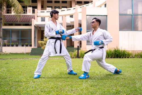 Preview: Asian Indonesian men sparring in karate training outdoors with protective gear