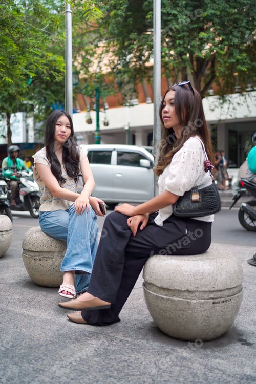 Preview: Gen Z Female Friends Sitting on Street Furniture in Yogyakarta