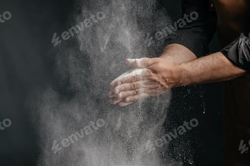 Preview: Chef clapping hands with flour dust cloud on dark background