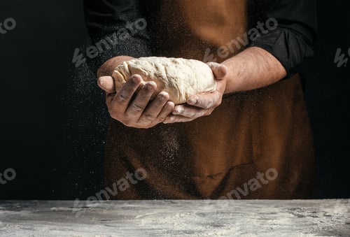 Preview: Baker holding dough with falling flour dust, artisan bread making concept