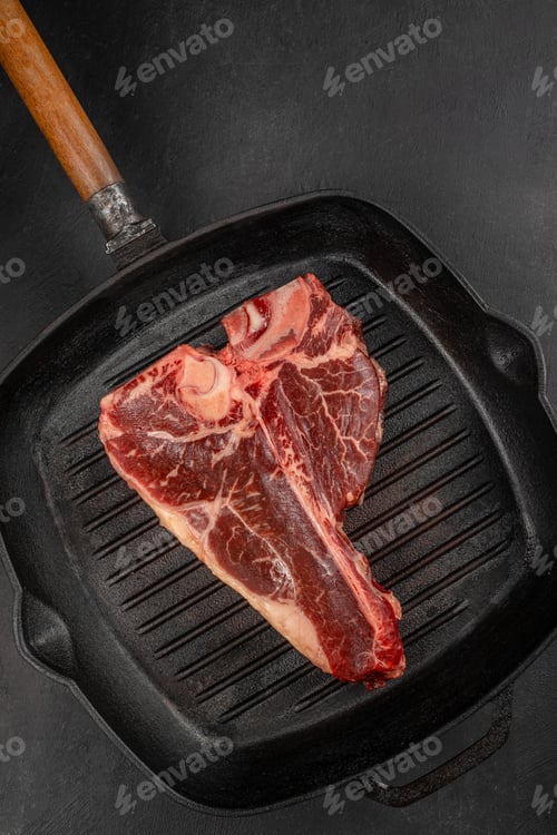 Preview: Raw porterhouse t bone steak in cast iron grill pan on dark background