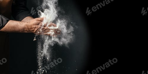 Preview: Chef clapping flour in air on dark background with large copy space baking concept