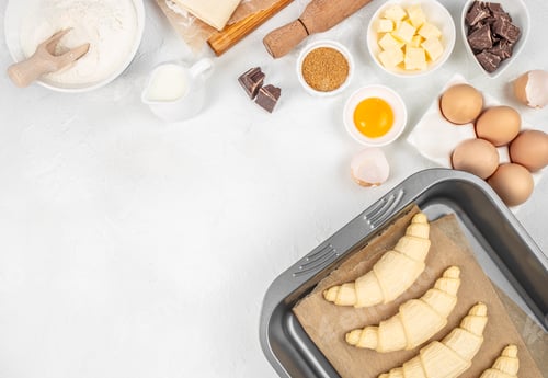 Preview: Croissant dough preparation with baking ingredients on white background, top view flat lay