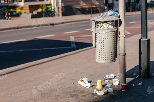 Preview: Overflowing street trash bin with litter scattered on sidewalk in urban area