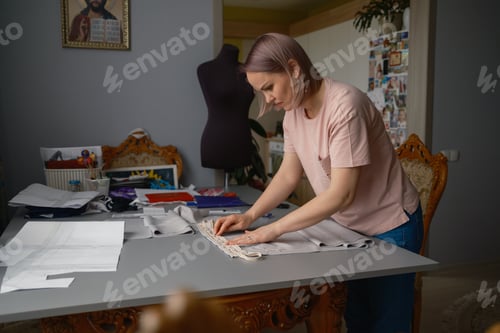 Preview: Woman seamstress working on fabric pattern in home sewing workshop preparing garment trim