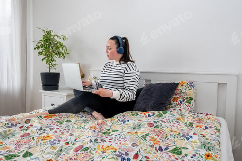Preview: Woman streaming content on laptop relaxing in bedroom evening