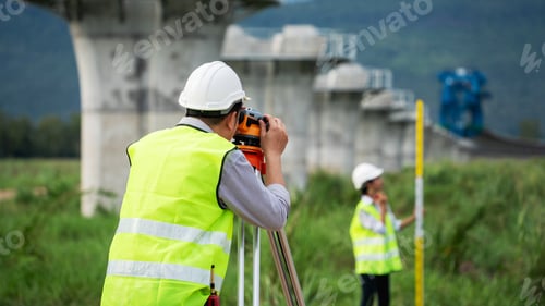 Preview: Civil engineers and survey team using a total station theodolite and road construction plans to meas