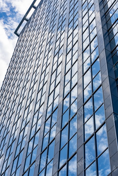 Preview: Clean and minimalist architectural detail of high-rise building glass panels reflecting clear sky an