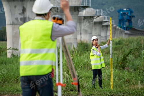Preview: Civil engineers and survey team using a total station theodolite and road construction plans to meas