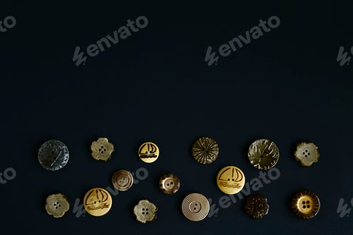 Preview: Collection of beautiful textured buttons with ornaments and pictures. Top view. Black background