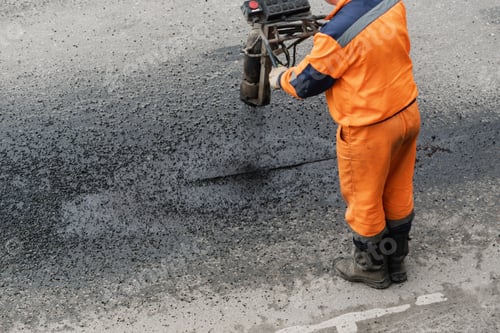 Preview: Municipal road worker applies hot bitumen to damaged asphalt seam during pavement repair