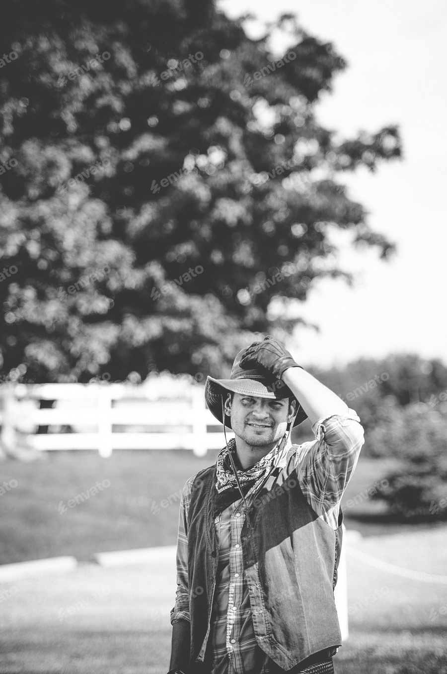 Cover for Vertical grayscale shot of a male wearing a cowboy outfit whit his hand on the hat