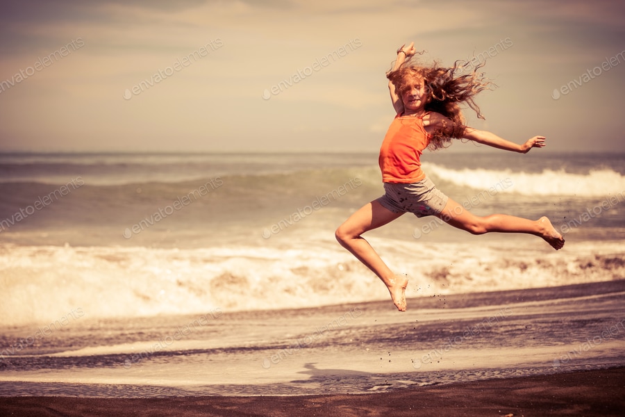 teen girl jumping on the beach at blue sea shore