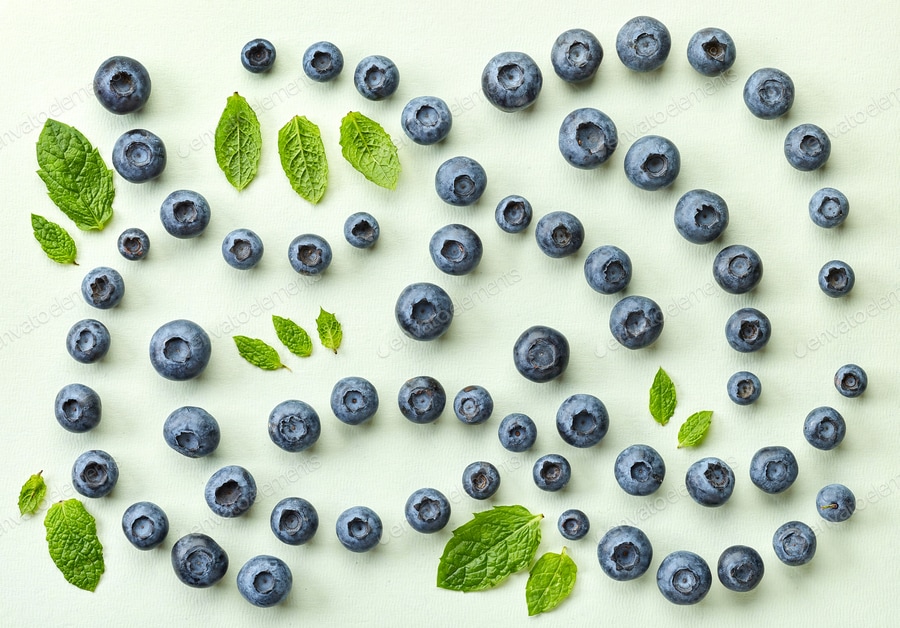 fresh blueberries on light green paper background
