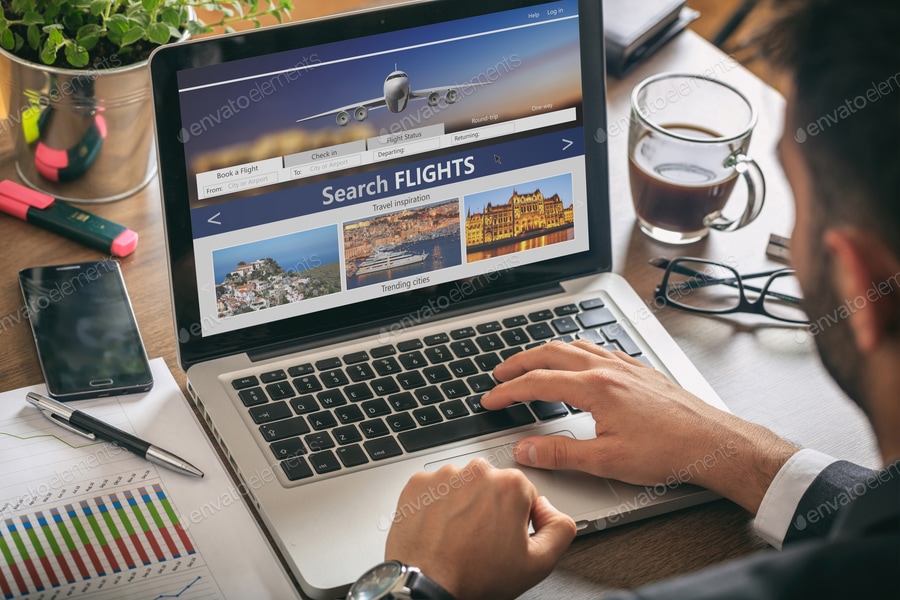 Man working with a computer, search flights on the screen, office business background.