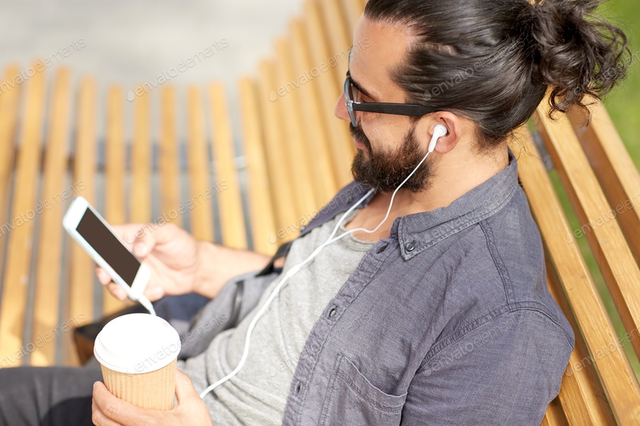 man with earphones and smartphone drinking coffee