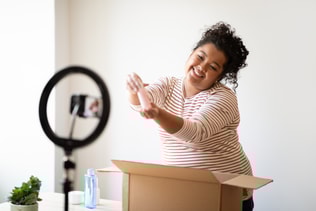 Woman plus size beauty blogger unpacking parcel, showing beauty product