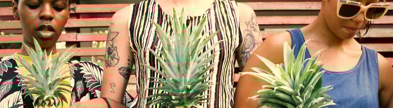 Group of diverse women standing holding pineapple together