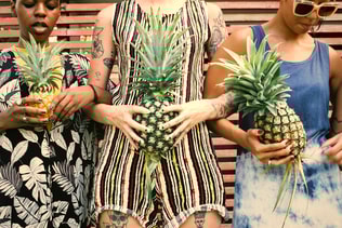 Group of diverse women standing holding pineapple together