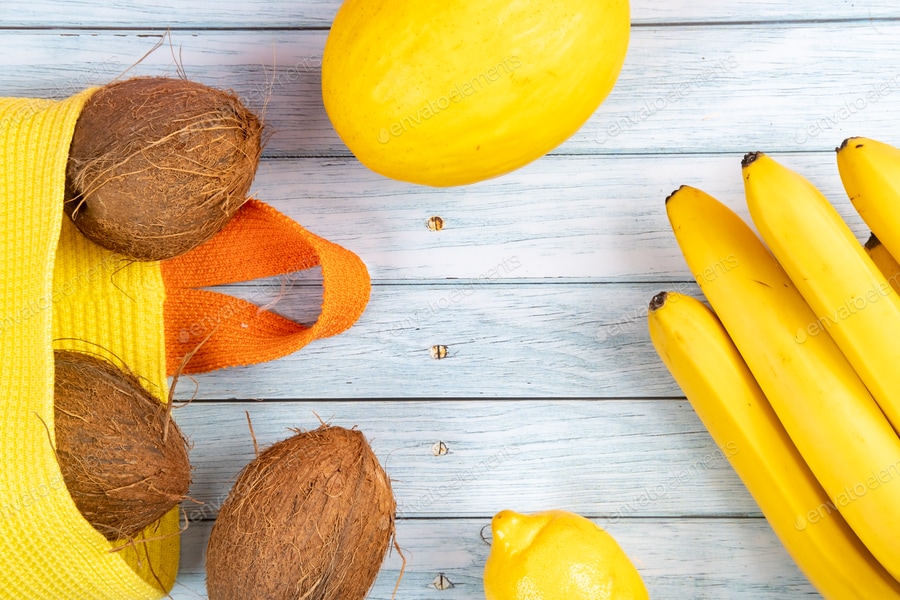 Cover for Whole coconuts in a yellow bag, bananas and melon on a blue wooden background