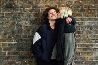 Young couple enjoying Camden town in front of a brick wall typical of London